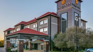 Un hotel con un llamativo letrero de 'La Quinta', un acceso cubierto y un césped bien cuidado.