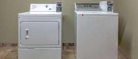 Two stacked washers in a corner with a tiled floor.
