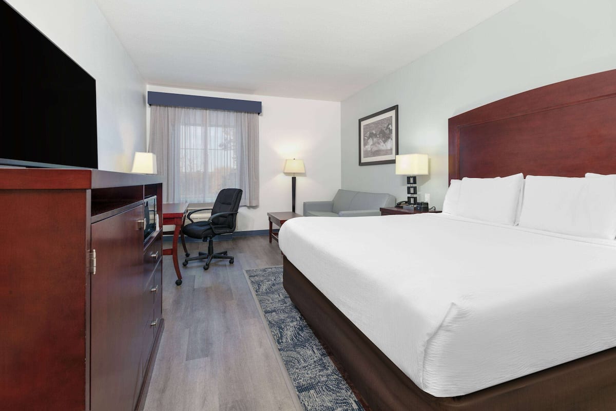 Een hotelkamer met een groot bed, een bureau met stoel, een televisie en een bureaulamp.