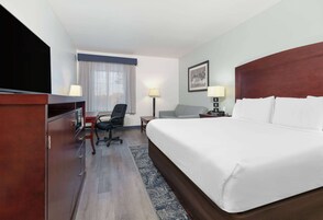 Habitación de hotel con una cama grande, un escritorio con silla, televisión y una lámpara de escritorio.