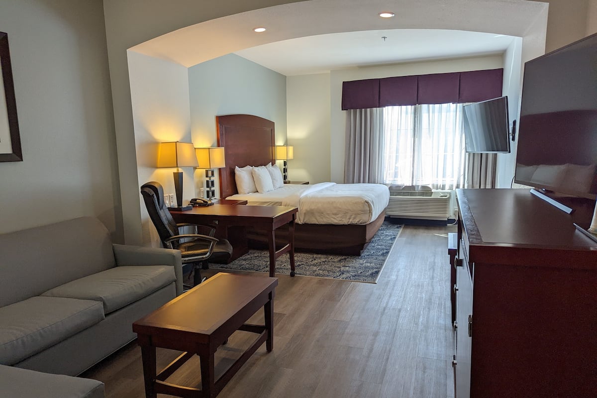 Een hotelkamer met een bed, bureau, stoel, televisie en een bank.