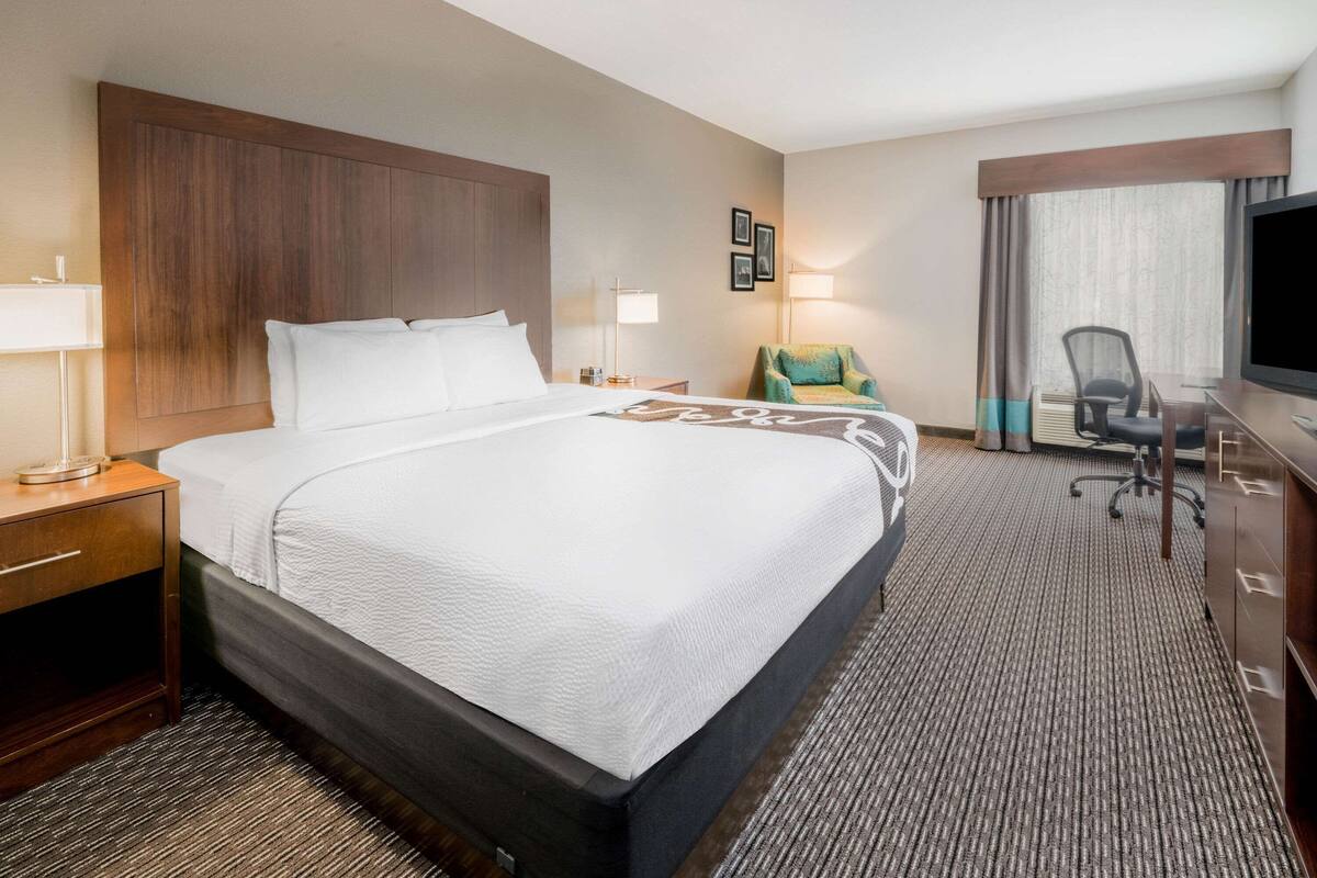 Hotelkamer met een groot bed, een bureau, een stoel, een televisie en een raam met gordijnen.