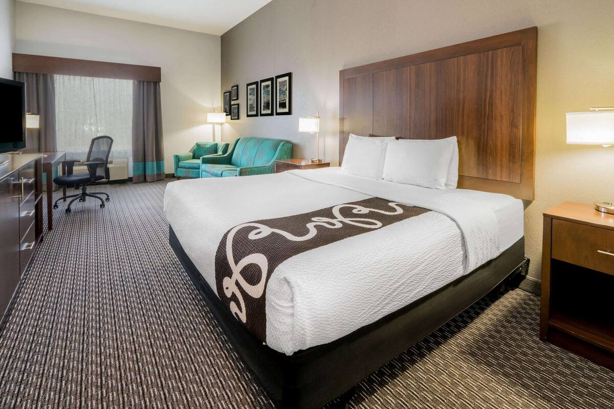 Een hotelkamer met een groot bed, een bureau, een stoel, een televisie en een bank.