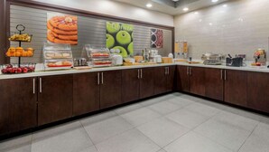 A modern kitchen area with a breakfast bar, various food items, and kitchen appliances.
