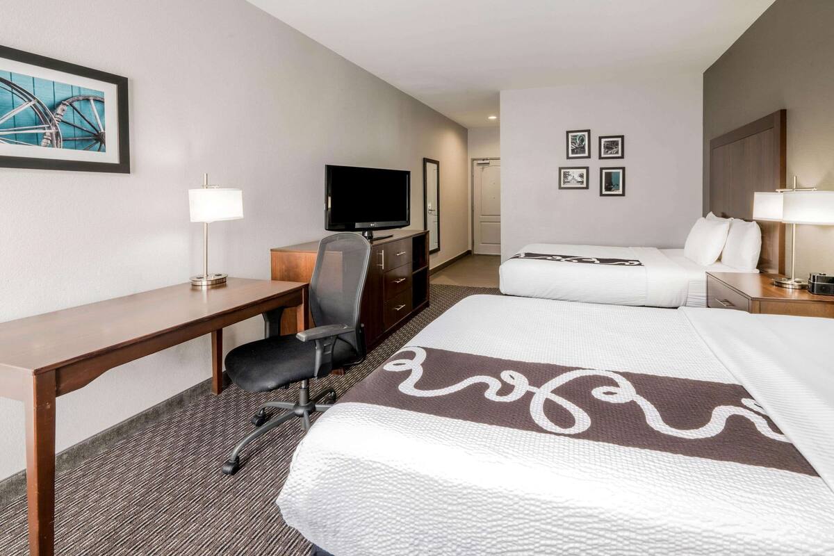 Een hotelkamer met een bed, bureau, stoel, televisie en kunstwerken aan de wanden.
