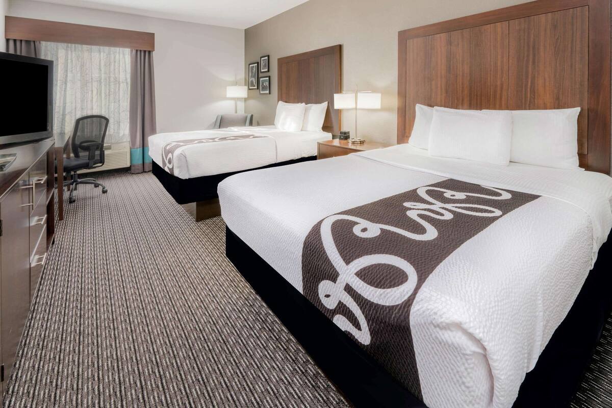 Een hotelkamer met twee bedden, een televisie, een bureau en een stoel.