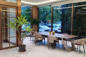 A modern dining area with a large table, chairs, and potted plants.