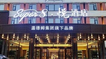 A hotel entrance with a sign reading 'Super8 Hotel' and a sign for 'Warm Hotel Group' below.