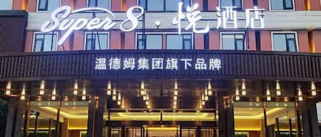 A hotel entrance with a sign reading 'Super8 Hotel' and a sign for 'Warm Hotel Group' below.
