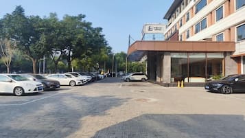 Un estacionamiento con autos, un edificio con un letrero y árboles.