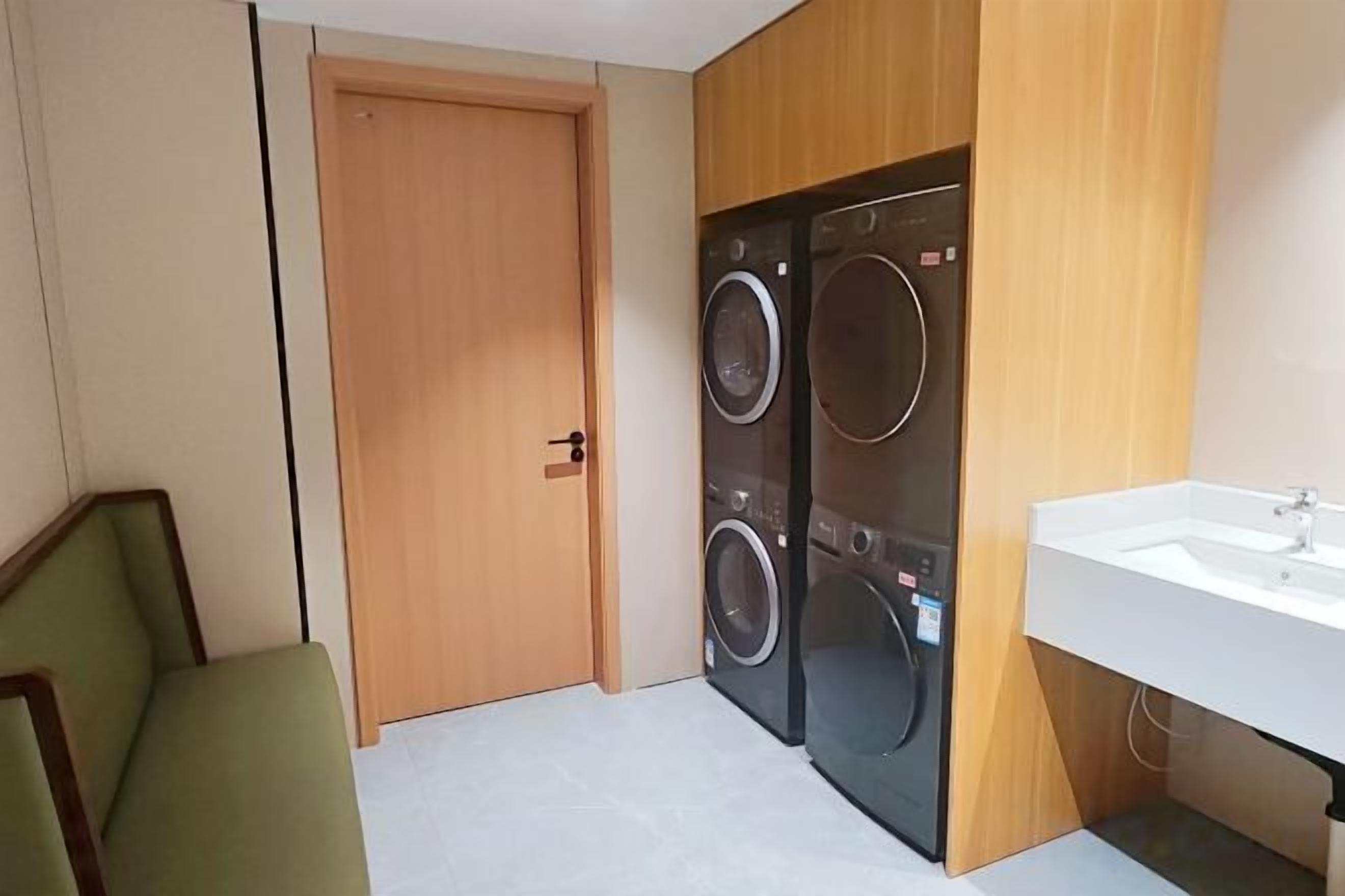 A compact room with a washing machine, a sink, and a door.
