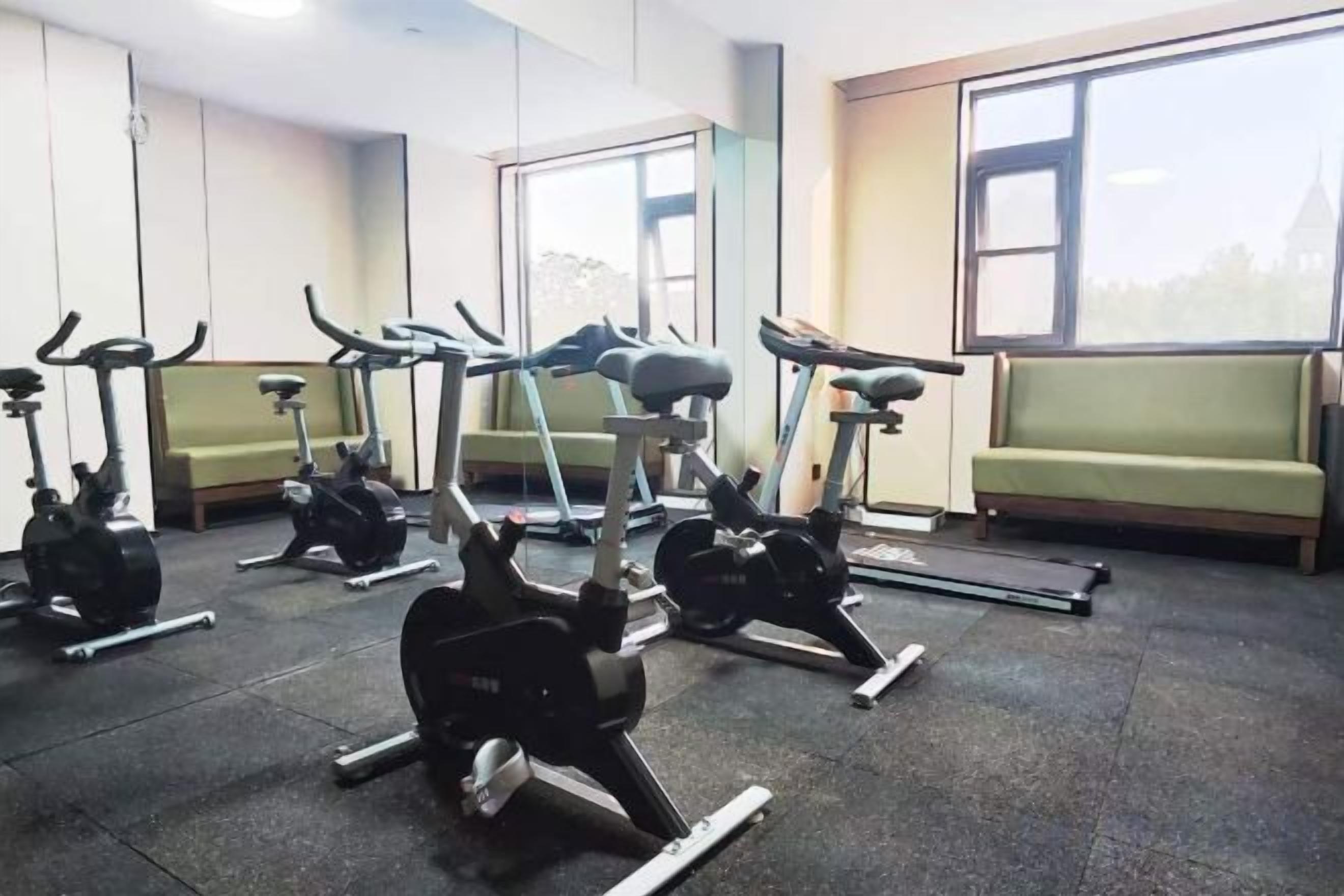 A gym with stationary bikes, a treadmill, and a bench.