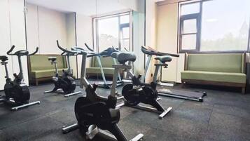 A gym with stationary bikes, a treadmill, and a bench.