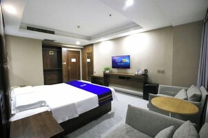 Una habitación de hotel con cama, televisión, sofá, una mesita y un escritorio.