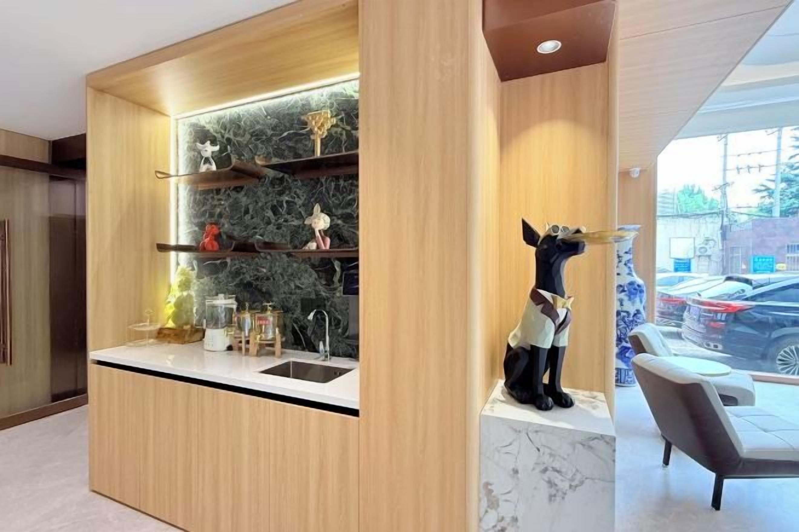 A modern kitchen with built-in shelves, a marble countertop, and a decorative dog statue.