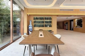 A conference room with a long table, chairs, a vase, and a window with a view of greenery. - Super 8 Hotel (Xingtai Railway Station Tianyi Square Kaixuan Branch) (Xingtai)