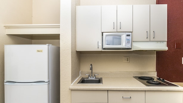 A compact kitchen with a refrigerator, microwave, sink, and stove. - Countryside Suites Kansas City Independence I-70E Sports Complex Hotel (Independence)