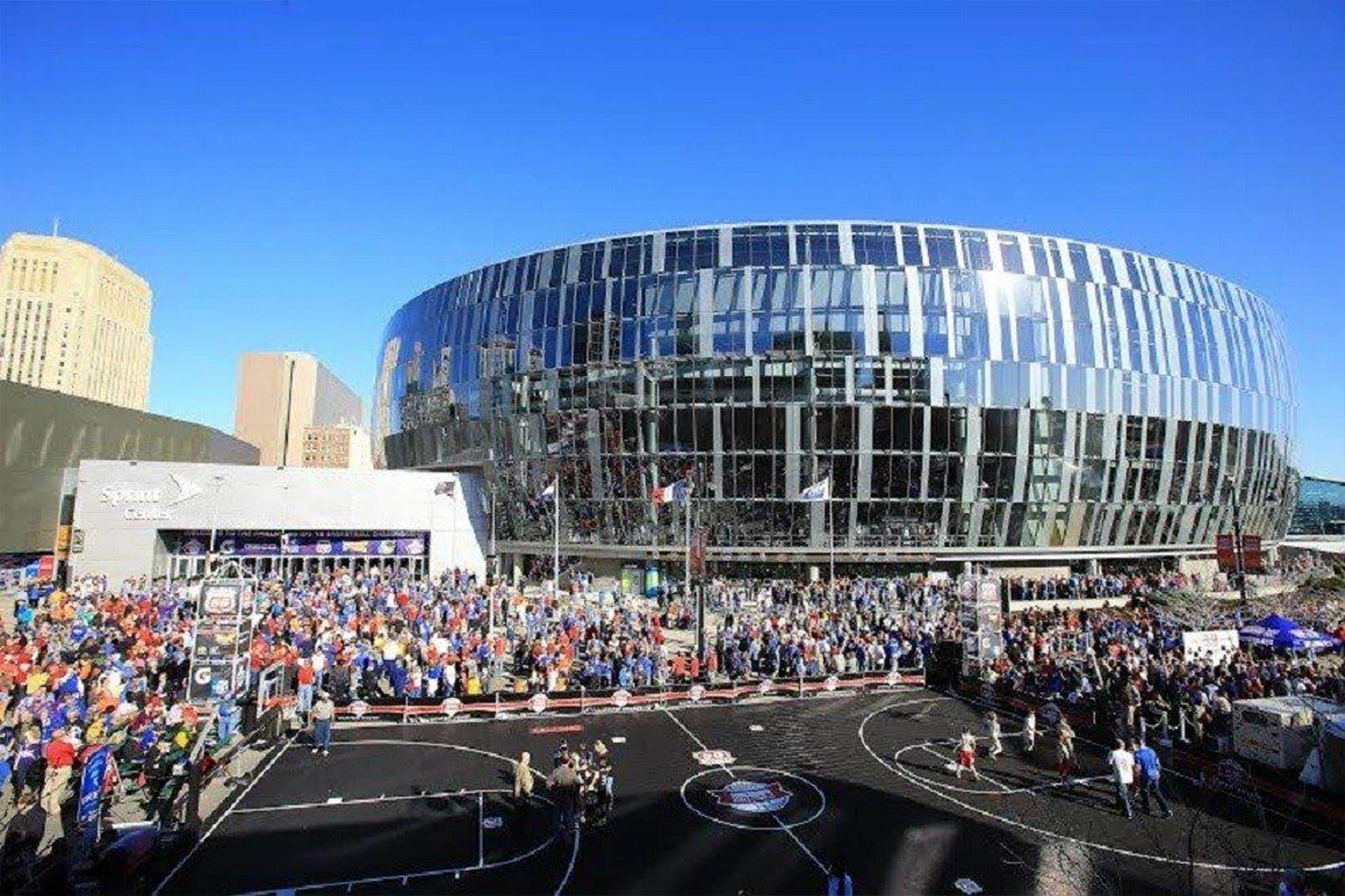 Un estadio moderno con fachada de vidrio curva, rodeado de una gran multitud.