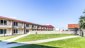 A multi-story motel with a red roof, stone wall, and a well-maintained lawn. - Countryside Suites Kansas City Independence I-70E Sports Complex Hotel (Independence)