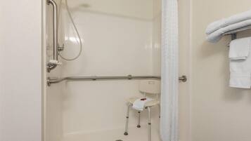 A shower area with a grab bar, a seat, and a towel rack.