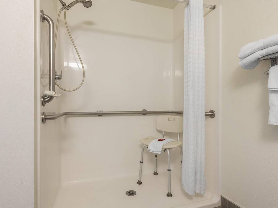 A shower area with a grab bar, a seat, and a towel rack.