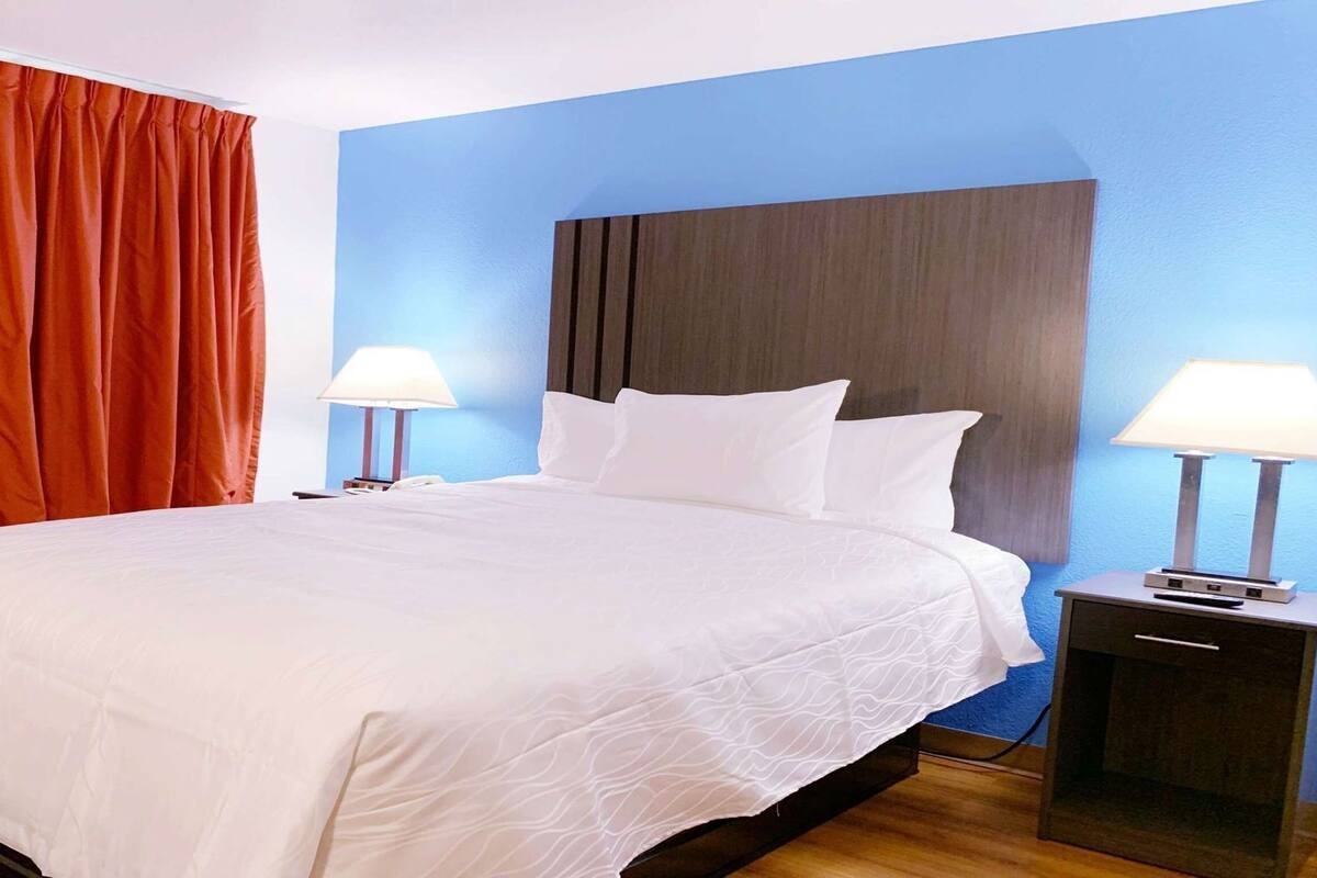 Une chambre d’hôtel avec un grand lit, deux tables de chevet avec des lampes et un mur d’accent bleu.