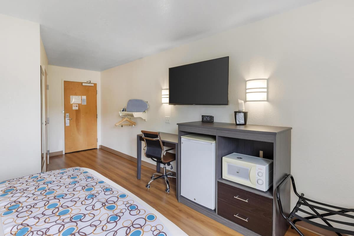 Une chambre d’hôtel équipée d’un lit, d’un bureau avec un ordinateur, d’un four à micro-ondes et d’une chaise.