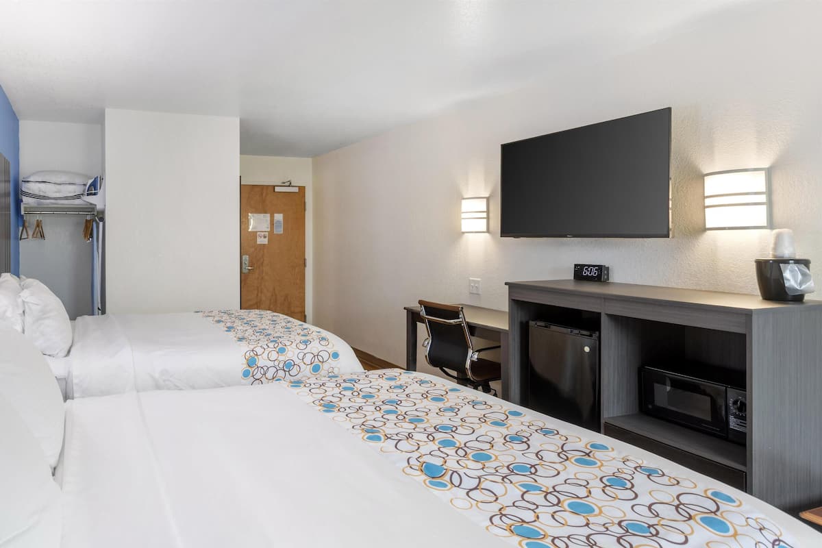 Une chambre d’hôtel avec deux lits, un bureau, un four à micro-ondes et une télévision.