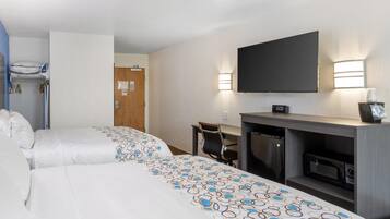 A hotel room with two beds, a desk, a microwave, and a TV.