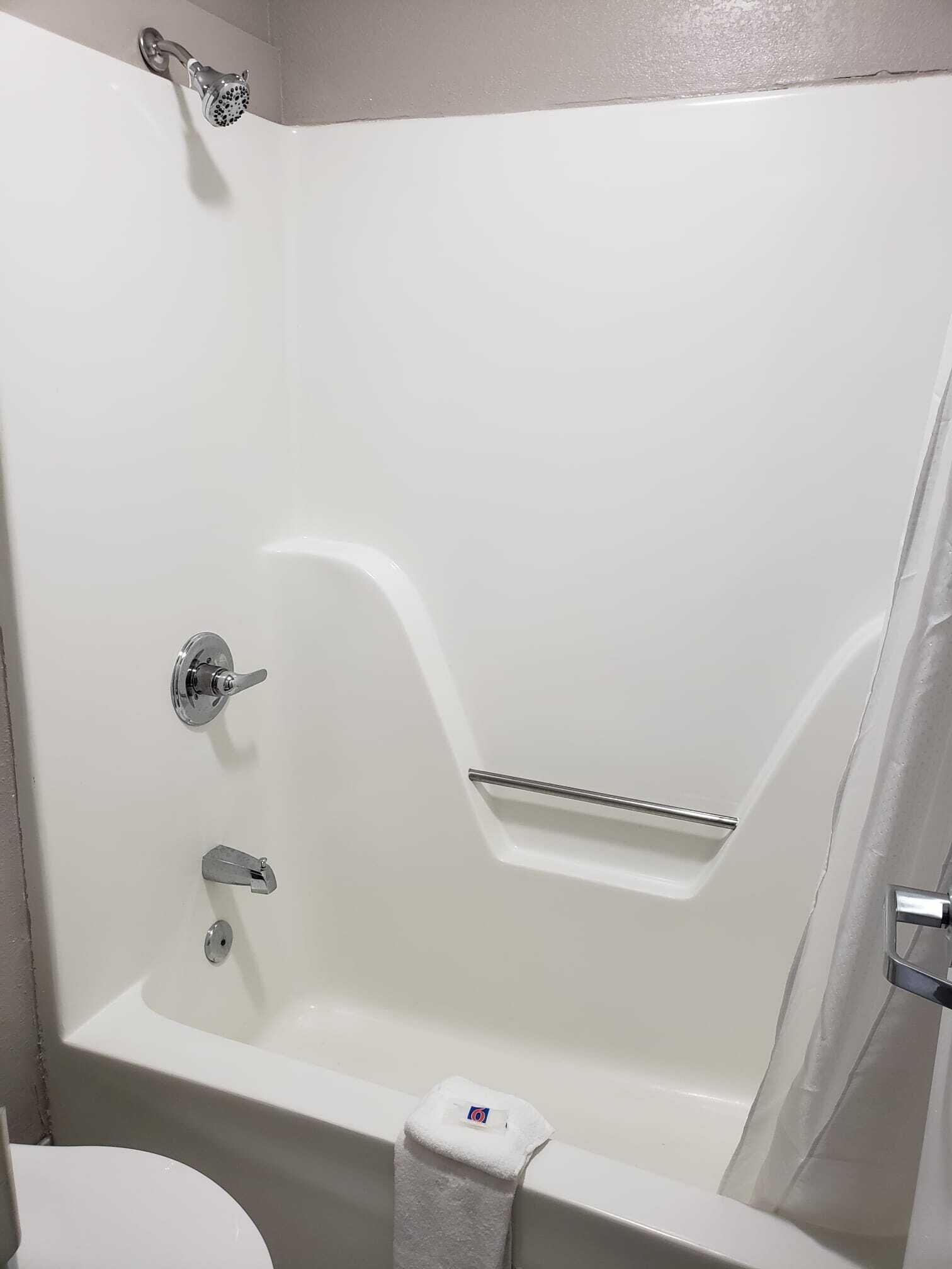 A white bathtub with a showerhead, a faucet, and a towel rack.