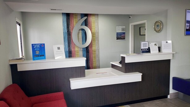 Un espace d’accueil avec un grand chiffre « 6 » peint sur le mur, un comptoir d’accueil, une chaise rouge et un tapis à rayures.