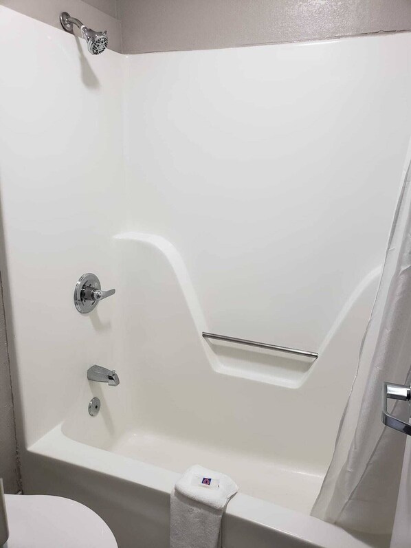 A white bathtub with a showerhead, a towel rack, and a toilet.