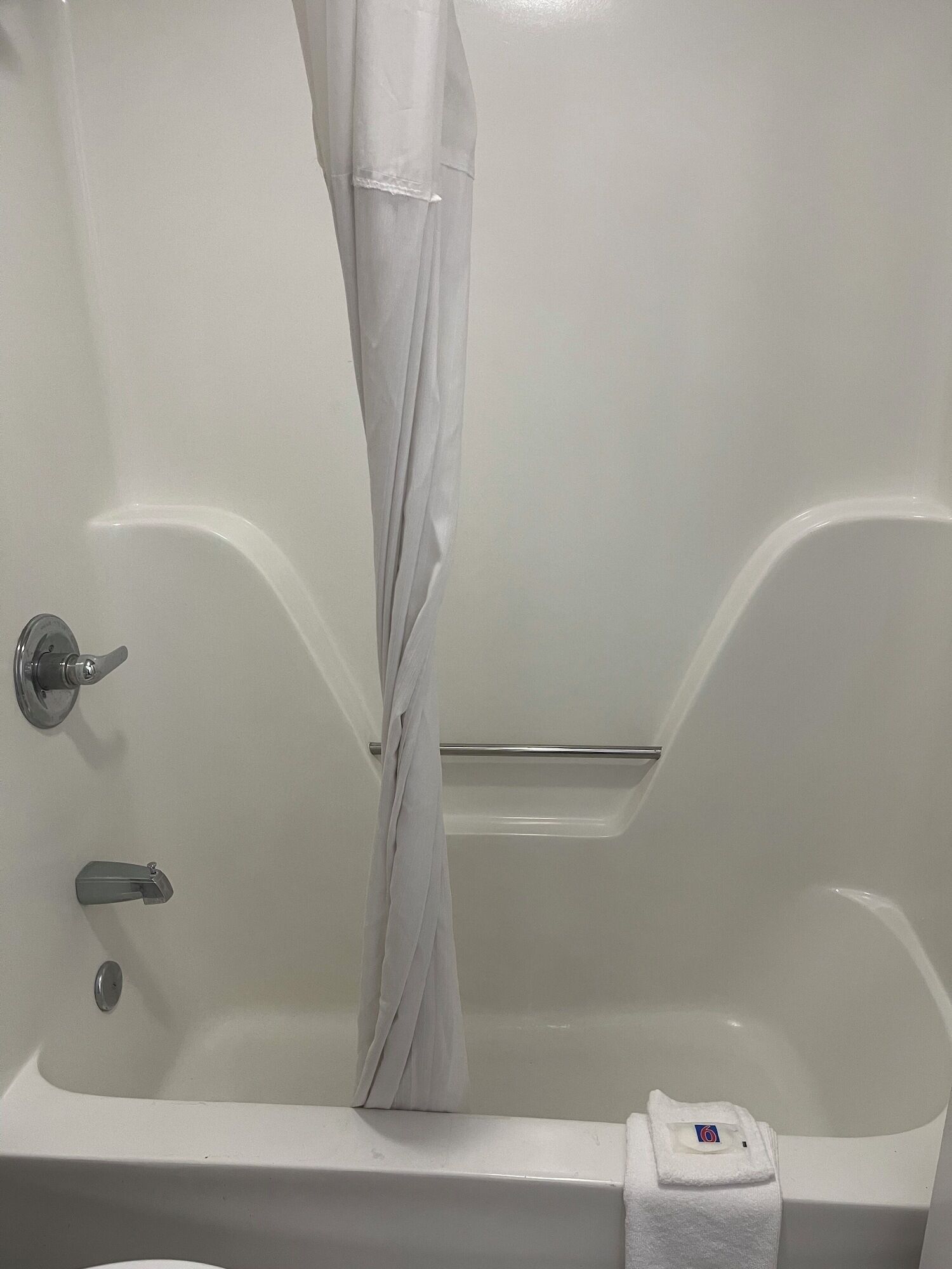 A white bathtub with a shower curtain, a towel, and a soap dish.