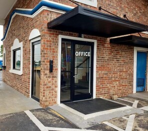 A brick building with a glass door labeled 'OFFICE' and a blue door. - Motel 6 East Ridge, TN (Chattanooga)