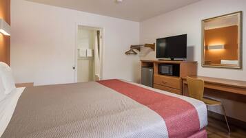 A hotel room with a bed, a desk, a television, and a mirror.