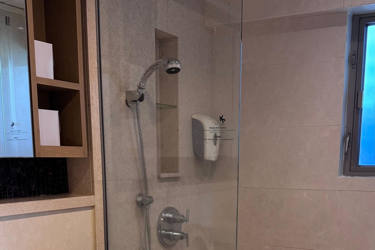 Un baño moderno con ducha de vidrio, inodoro y lavamanos integrado.