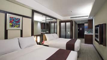 A hotel room with two beds, a large mirror, a painting on the wall, and a kitchenette in the background.