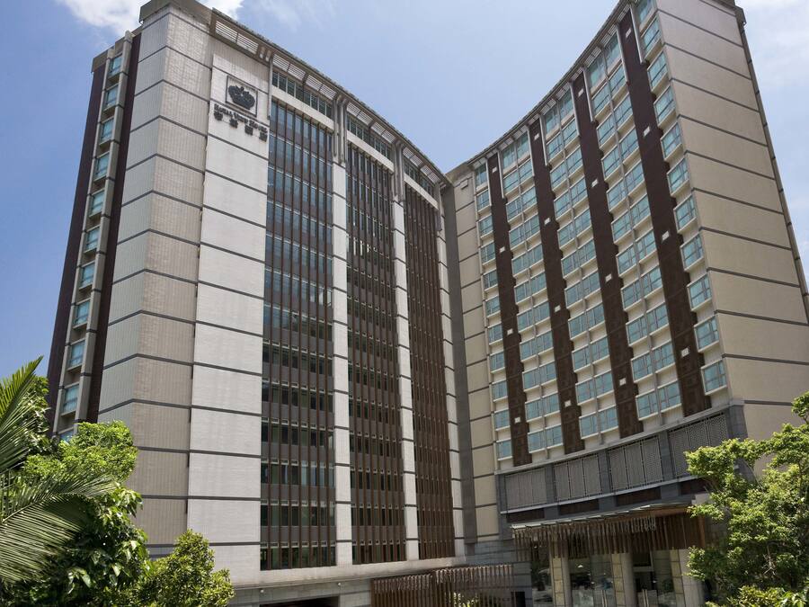A modern hotel with a central courtyard, a fountain, and a large entrance with a covered area.