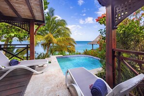 Ein Poolbereich mit Liegestühlen und Blick aufs Meer.