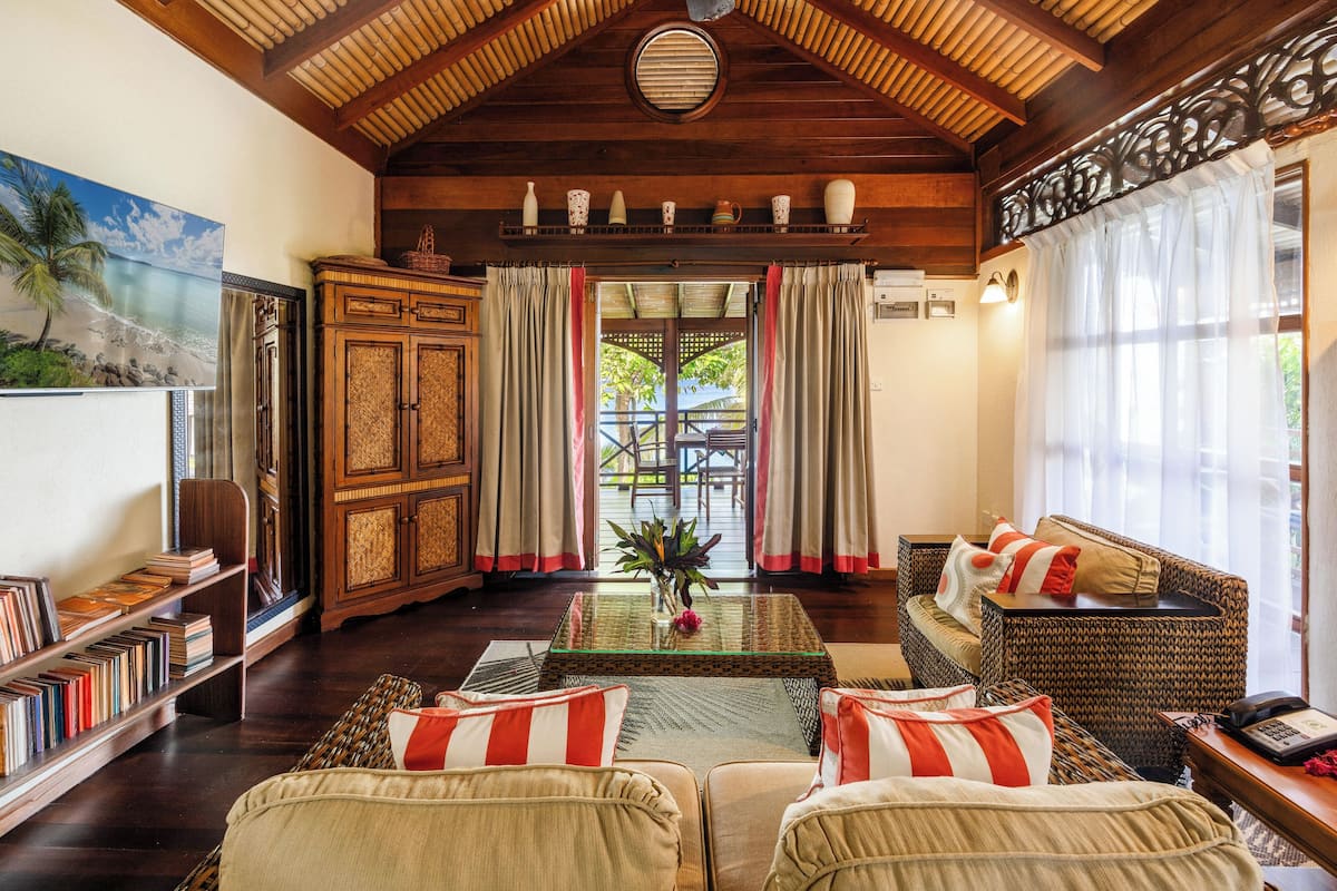 A cozy living room with a wooden ceiling, a bookshelf, a sofa set, and a coffee table.