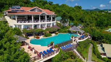 Alberca al aire libre, sombrillas en la alberca y camastros