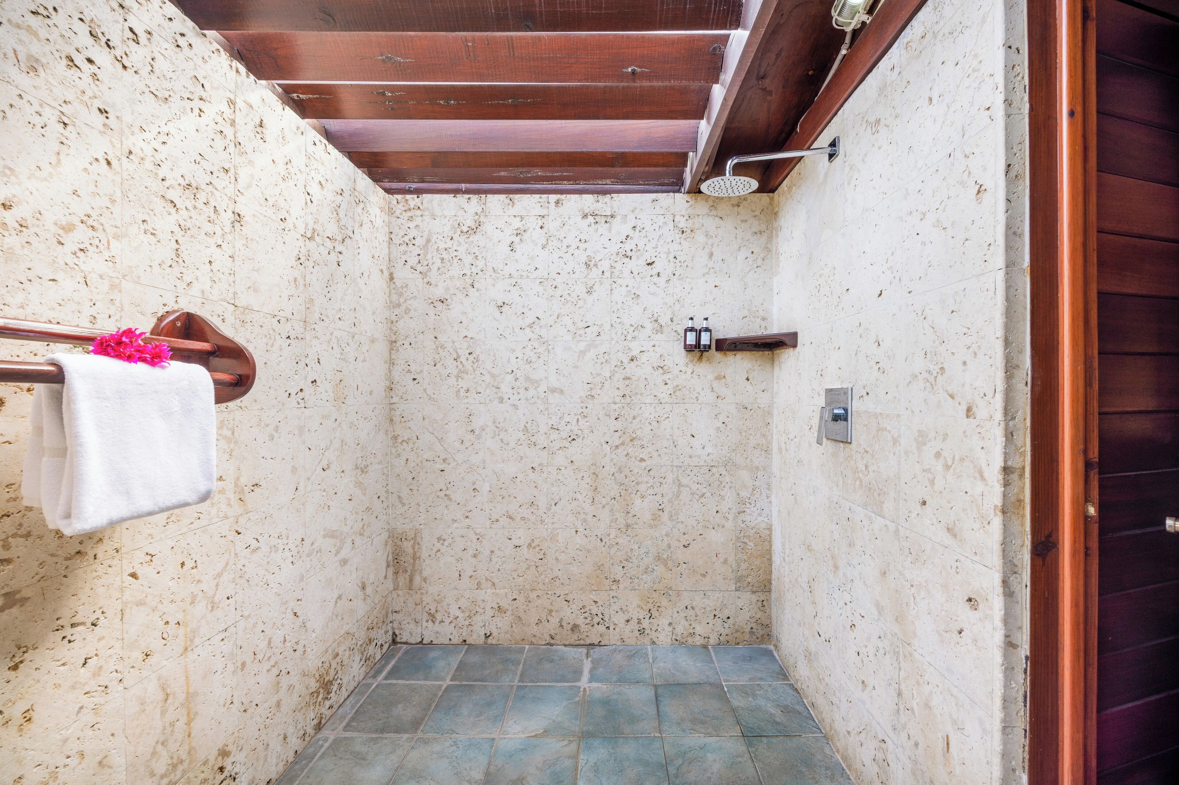 A small, enclosed shower area with a tiled floor and a wooden ceiling.