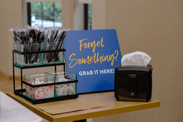 A table with a sign that says "Forget Something? GRAB IT HERE!" and a Dixie Ultra tissue dispenser.