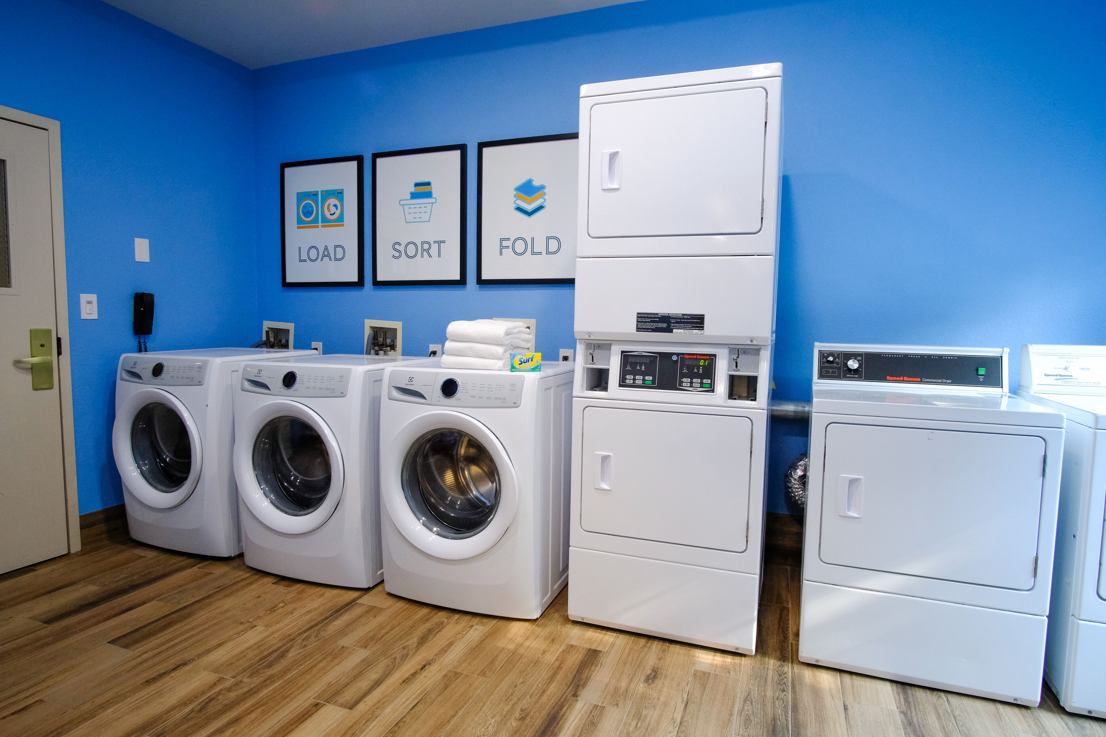A laundry room with four washing machines, a dryer, and a stacked washer-dryer unit.