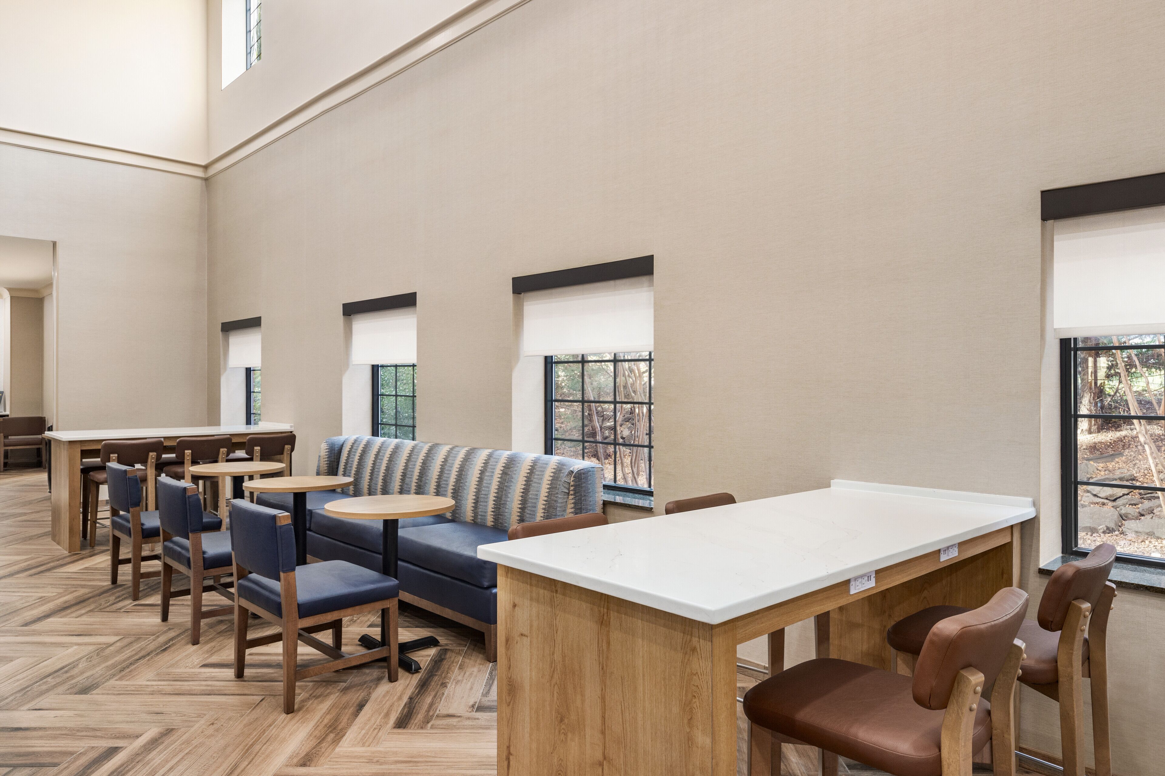 A spacious indoor area with a long wooden table, several chairs, a sofa, and a small round table.