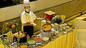 Mesa de buffet con diversos alimentos y un chef sirviendo.