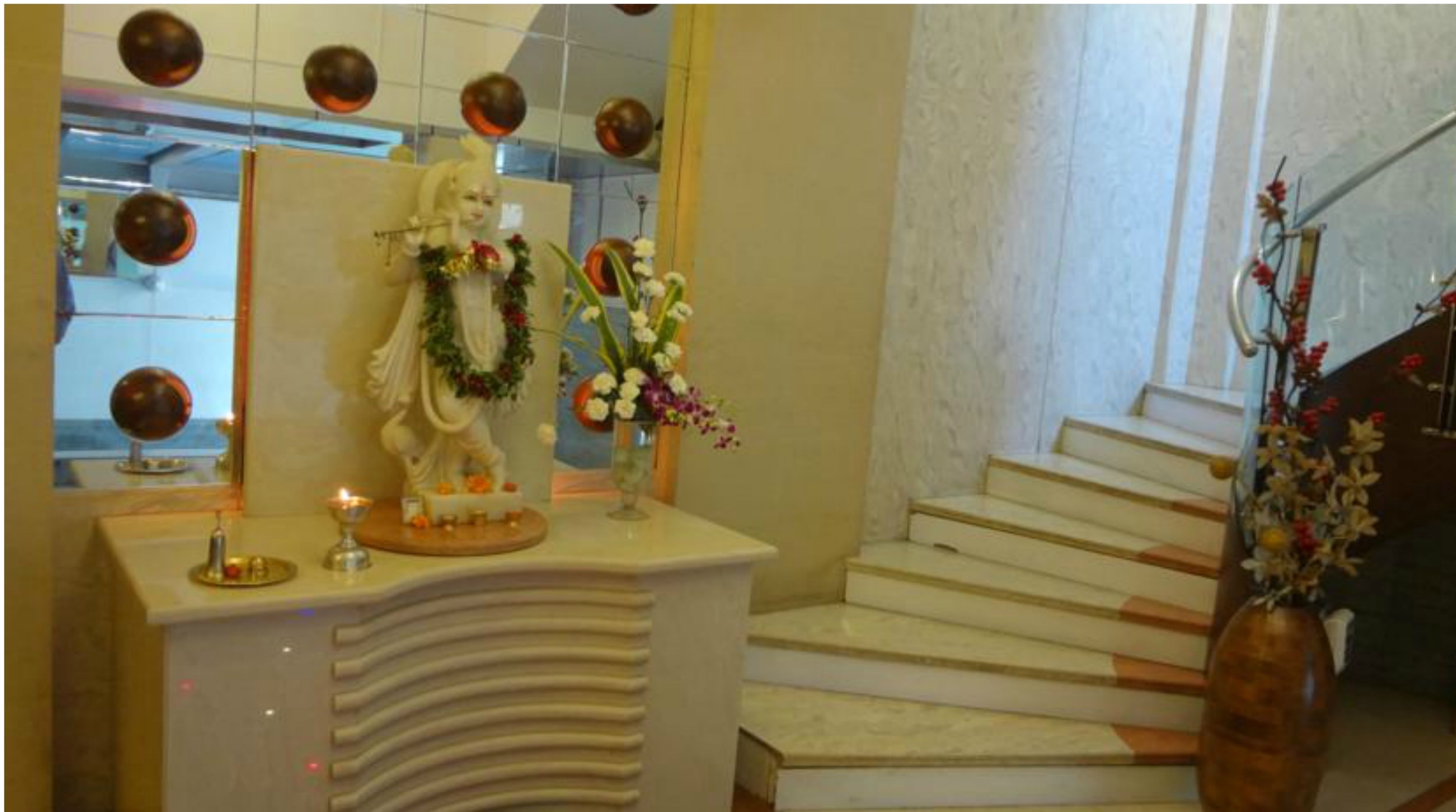 Un área de recepción con una estatua, un jarrón de flores y una escalera.