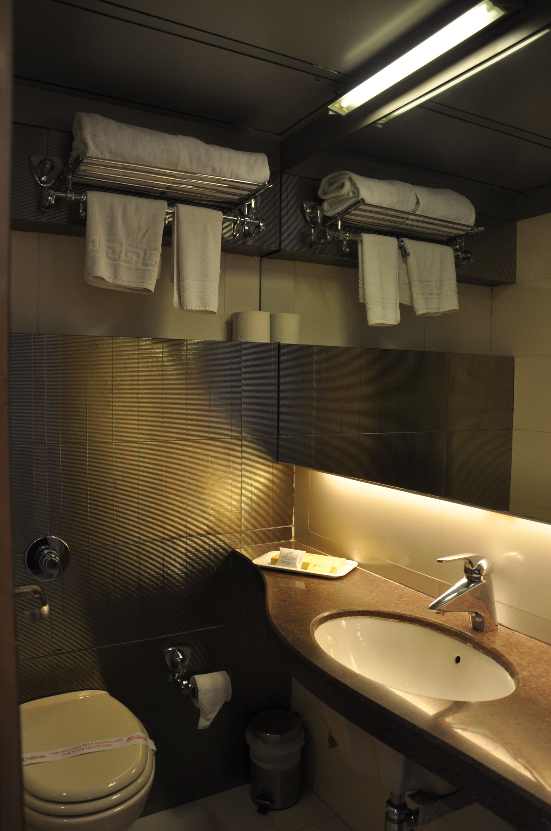 A compact bathroom with a toilet, sink, and towel rack.
