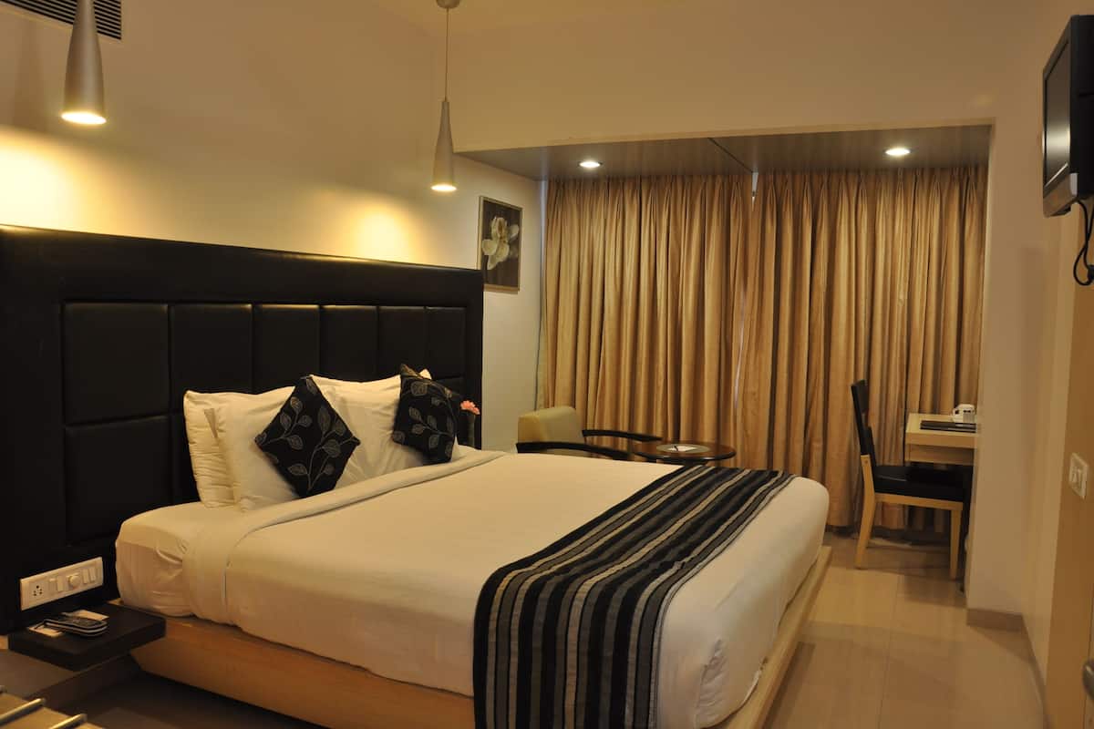 Una habitación de hotel con una cama grande, un escritorio, una silla y un televisor.