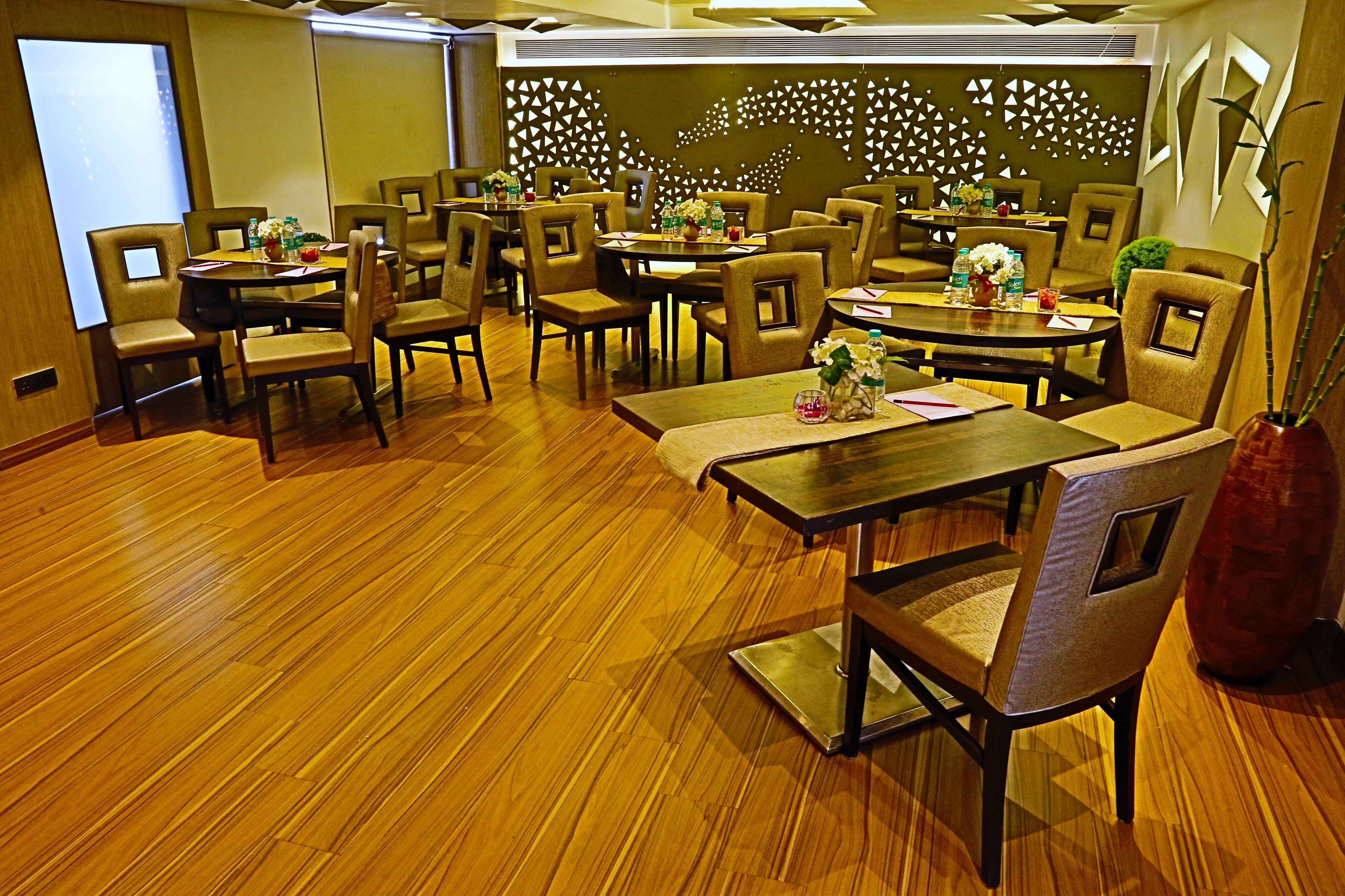 A conference room with multiple tables and chairs, equipped with water bottles and floral centerpieces.